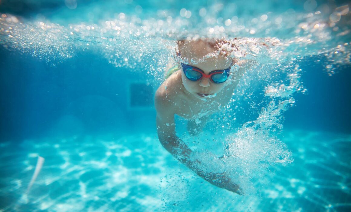 Boy swimming under water with goggles on
