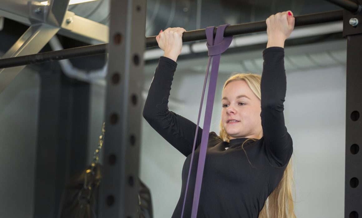 Young Woman doing pull ups in a gym